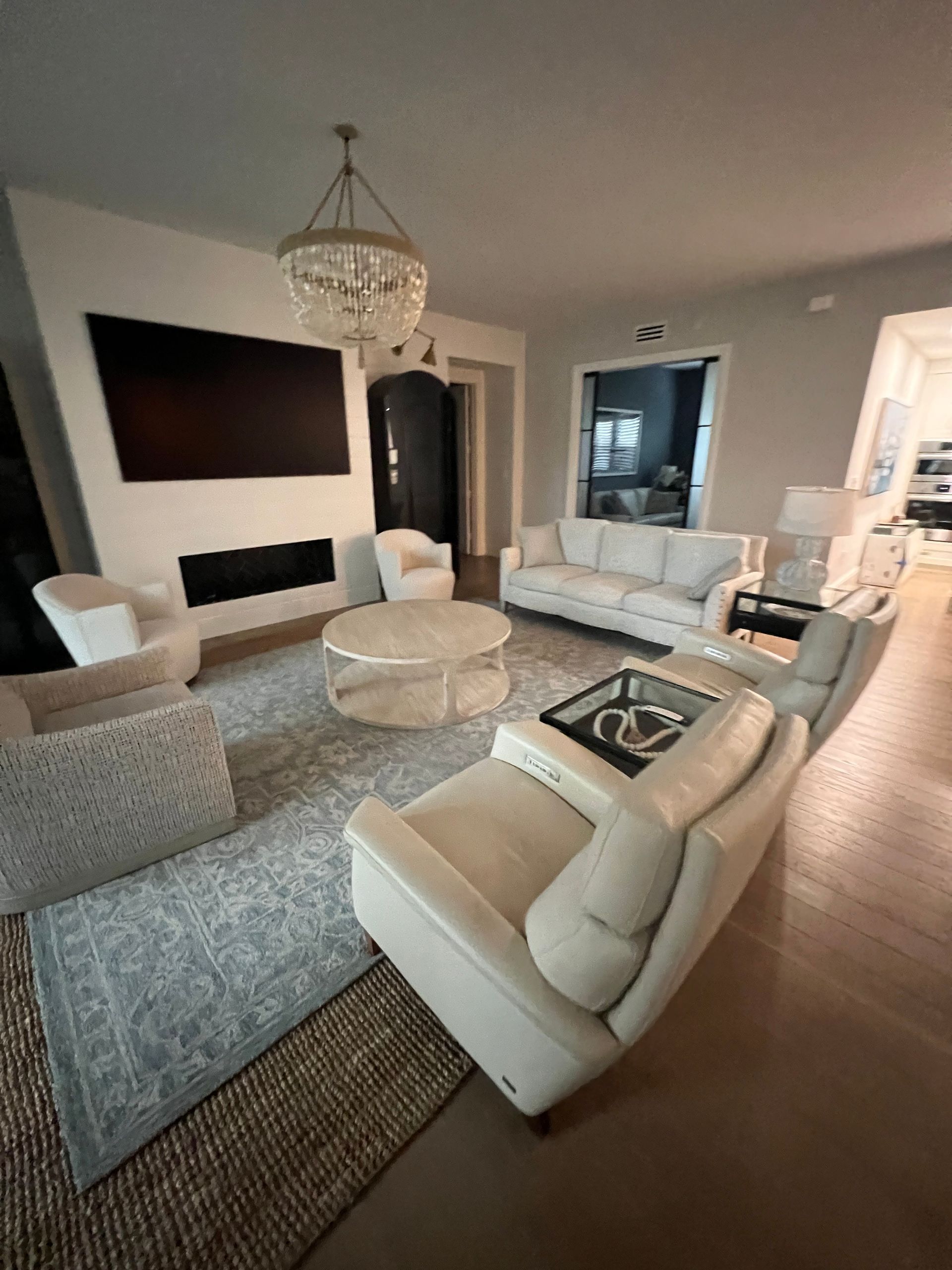 Modern living room with beige sectional, patterned rug, round coffee table, wall art, and light wood floors