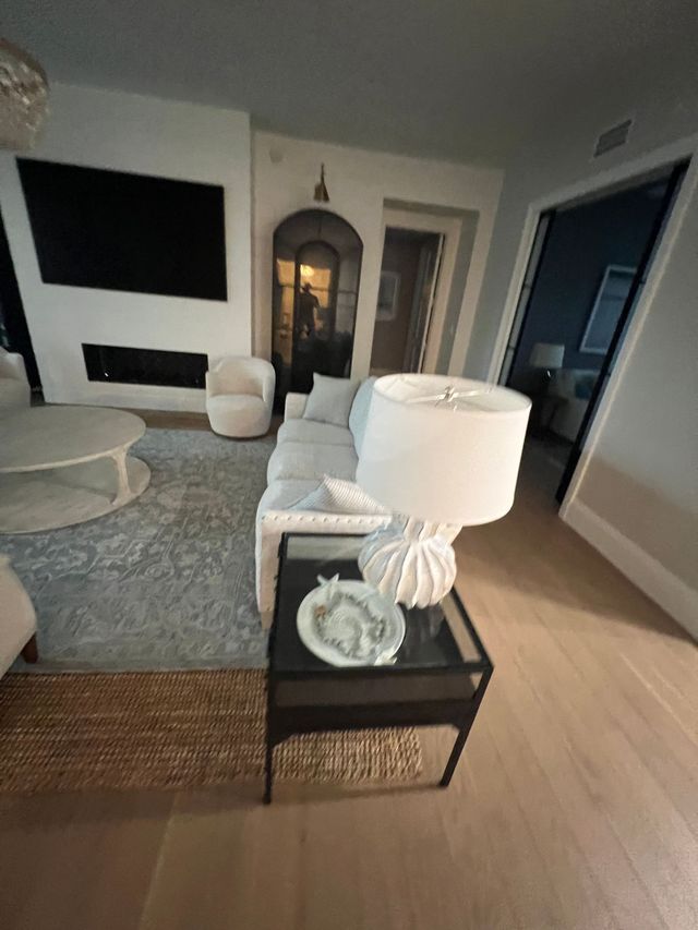 Modern living room with white sofa, black TV wall, arched mirror, and black side table with lamp and decor