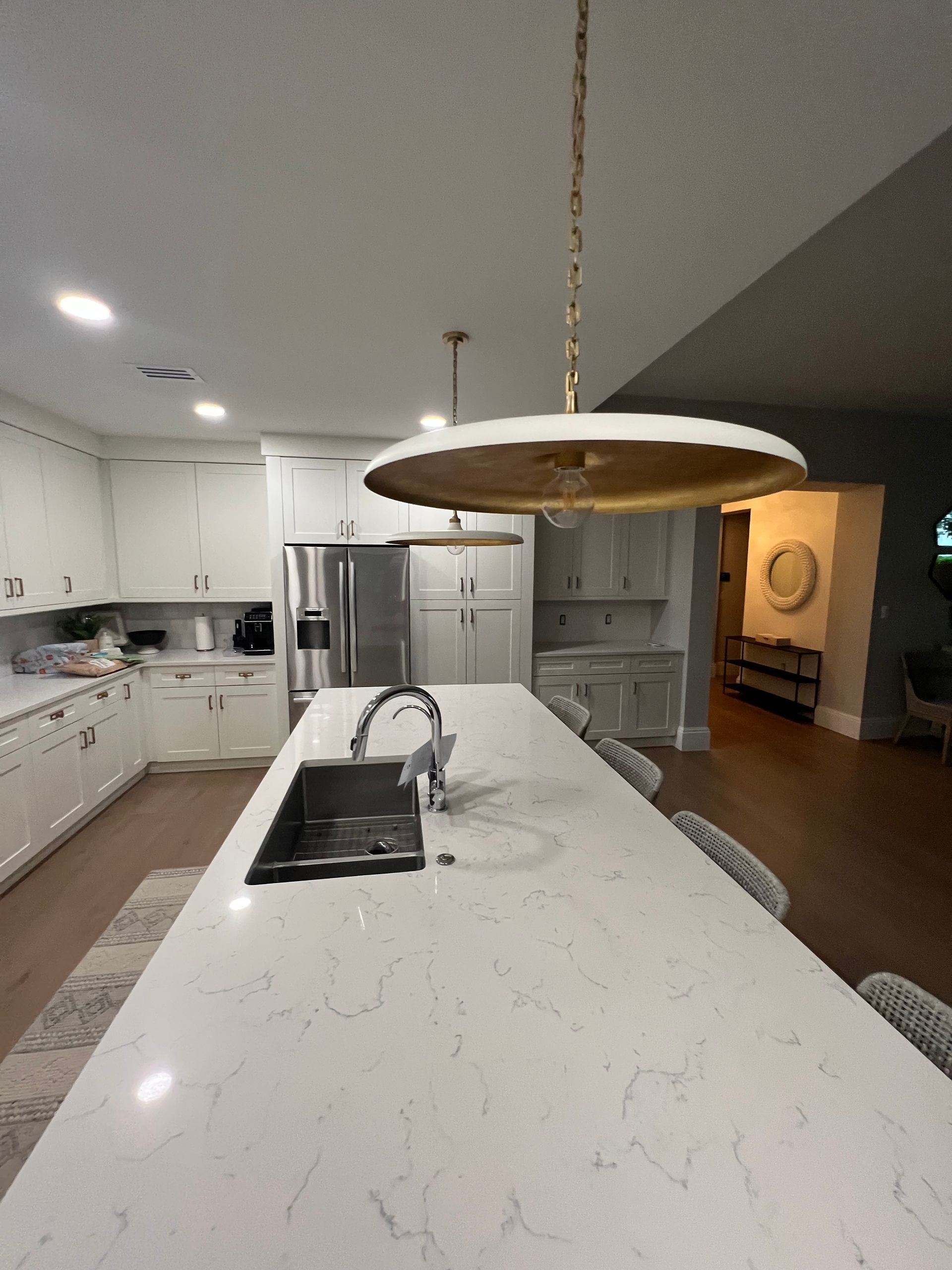 Modern kitchen with white cabinets, marble island, pendant light, and stainless steel appliances
