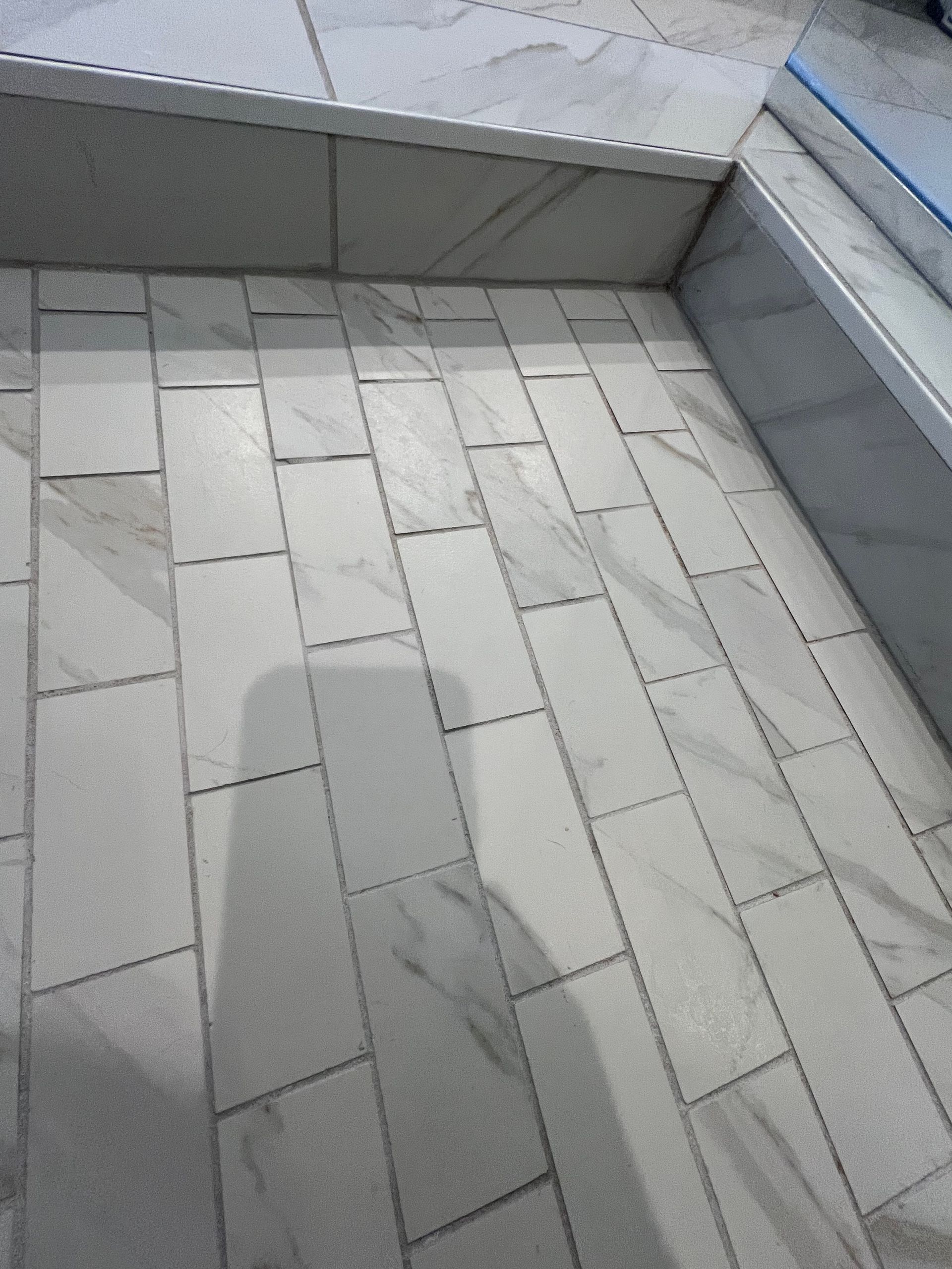 White tiled balcony floor beside a low gray wall and blue railing edge