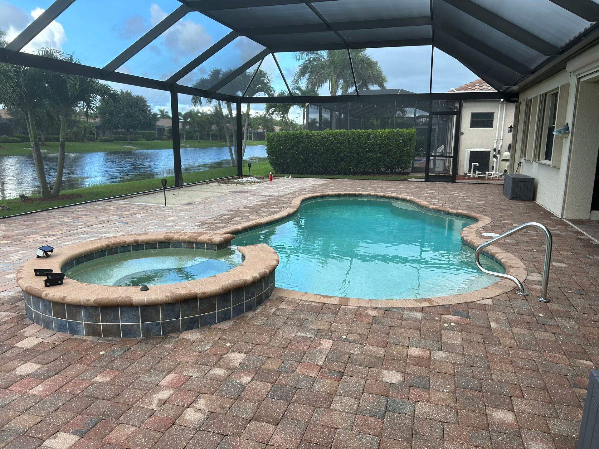Covered backyard pool and hot tub beside a patio overlooking a lake