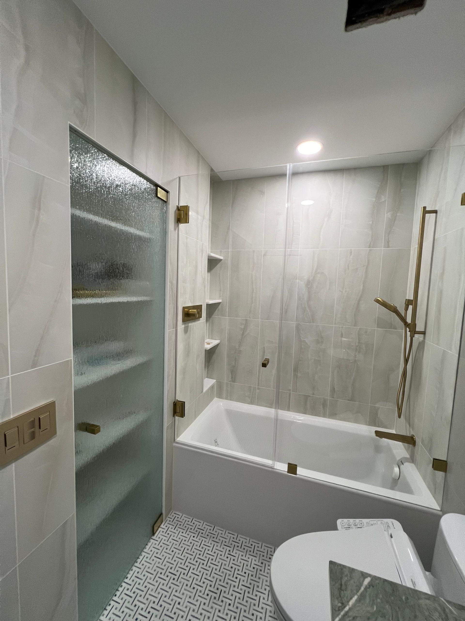 Bright modern bathroom with walk-in shower, bathtub, toilet, and built-in shelves.