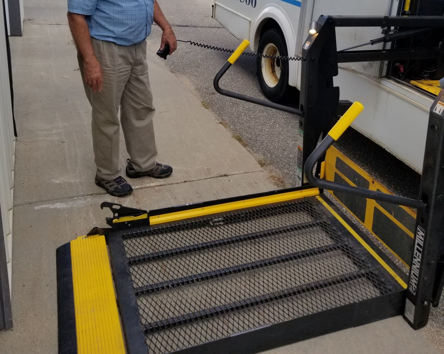 Bus lift in down position with person standing next to it