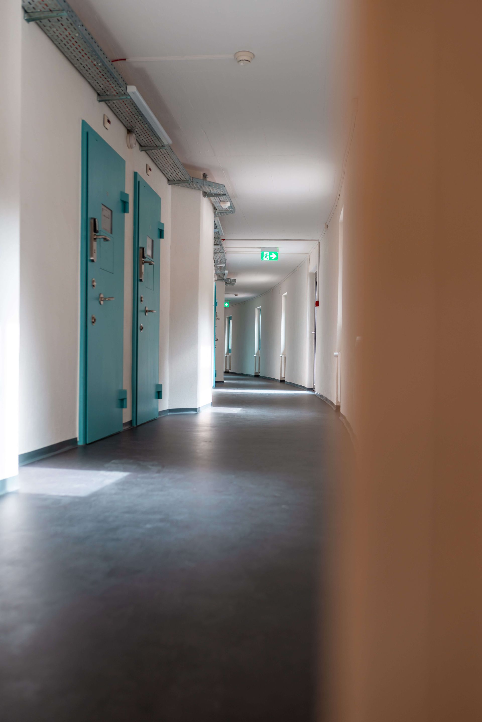 Ein langer Flur mit blauen Türen in einem Gebäude.