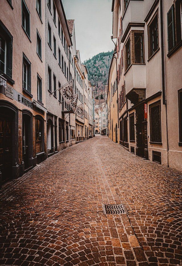 Eine schmale Kopfsteinpflasterstraße zwischen zwei Gebäuden mit einem Berg im Hintergrund.