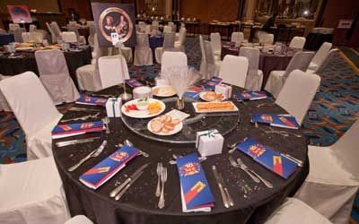 A round table with plates, silverware, napkins and a sign on it.