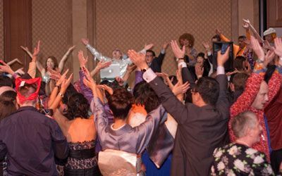 A group of people are dancing in a room with their hands in the air.