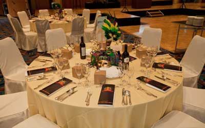 A round table with a white tablecloth and a bottle of wine on it.