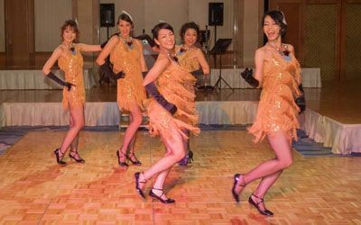 A group of people are dancing on a dance floor in a large room.