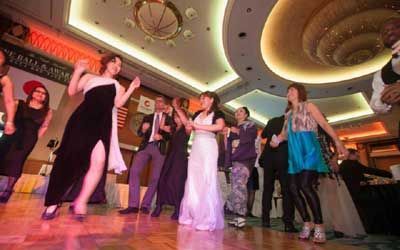 A group of people are dancing on a dance floor in a large room.