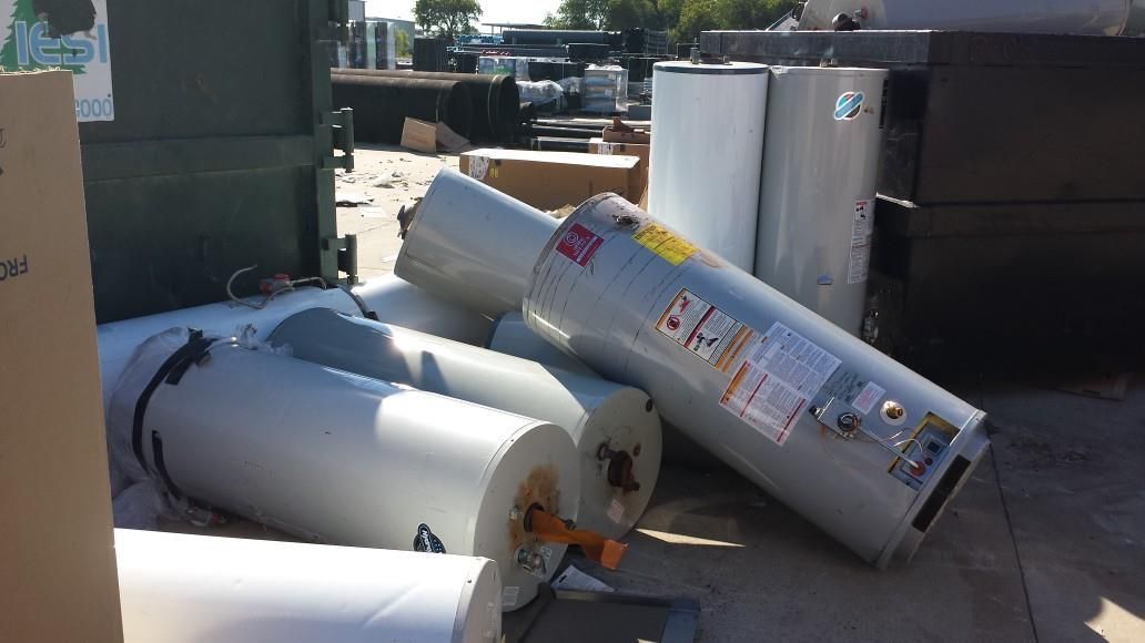 Several water heaters are stacked on top of each other on the ground.