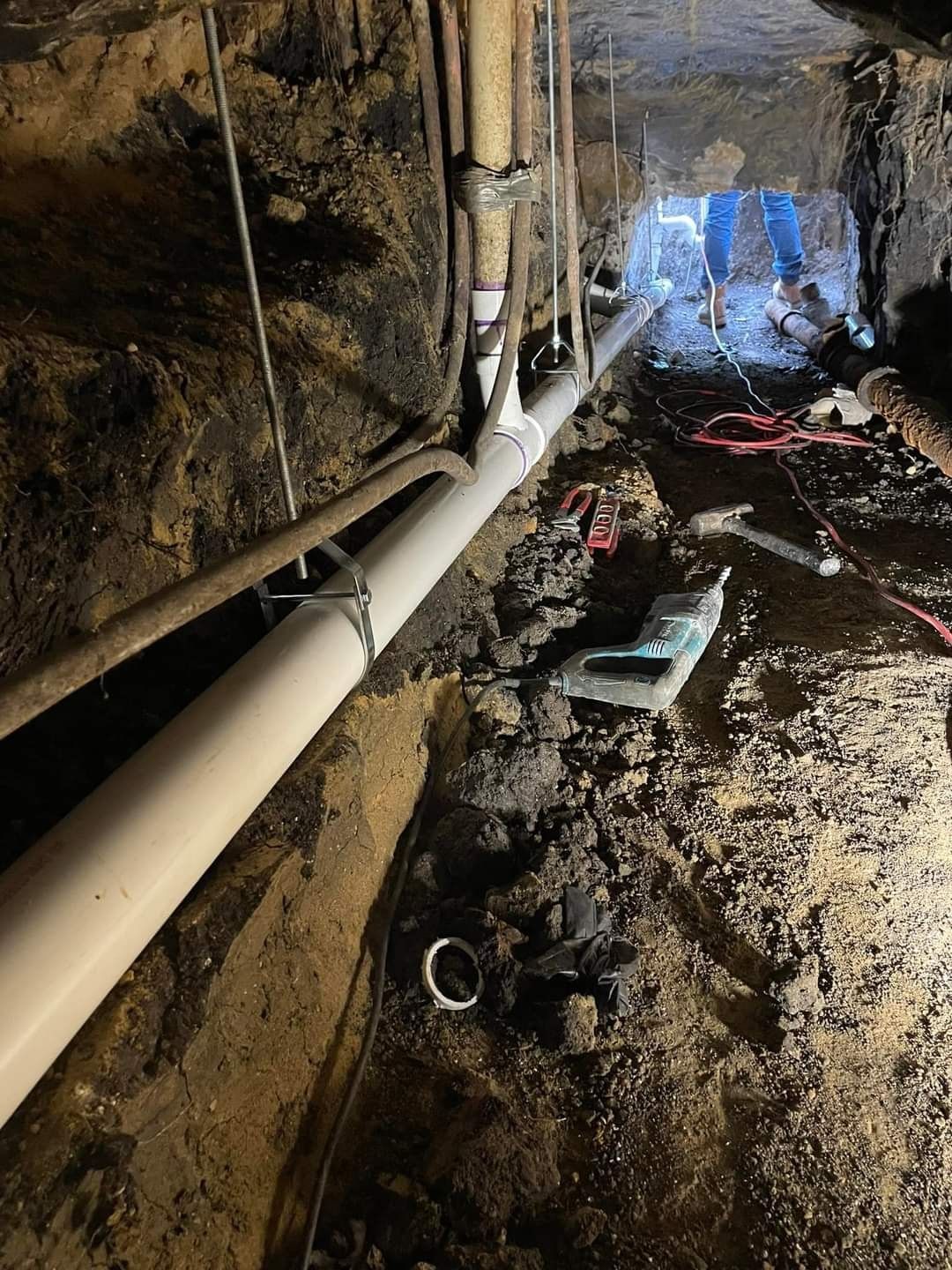 A person is working on a pipe underground.