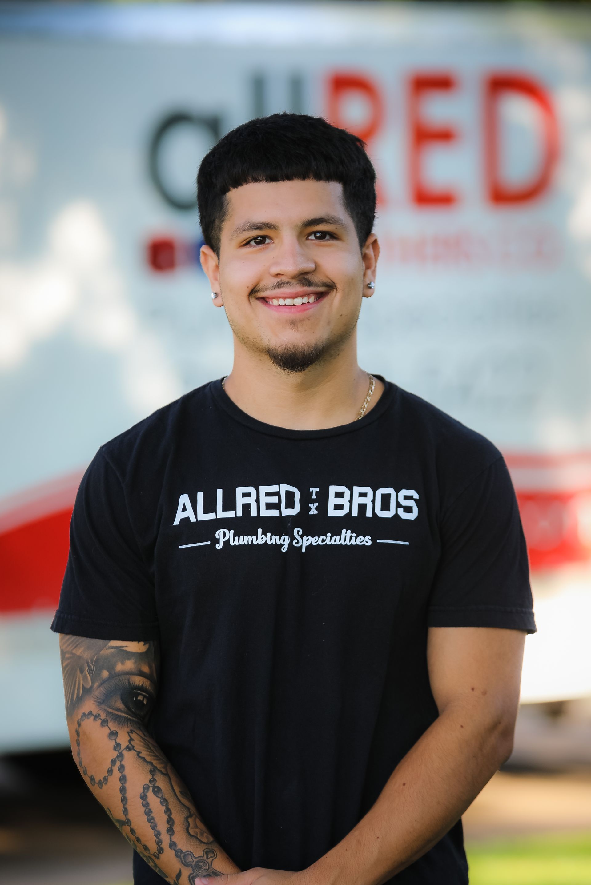 A man in a black t-shirt is standing in front of a truck.