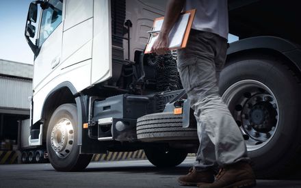 a man is standing next to a semi truck holding a clipboard