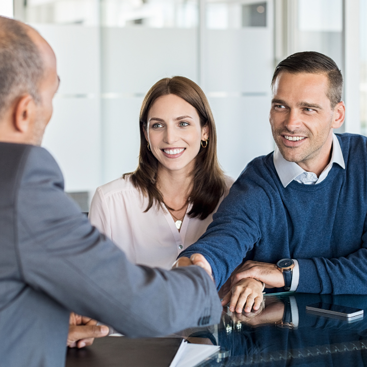 Couple smiling and shaking hands with chartered financial advisors in Maplewood after discussing their long-term financial goals.
