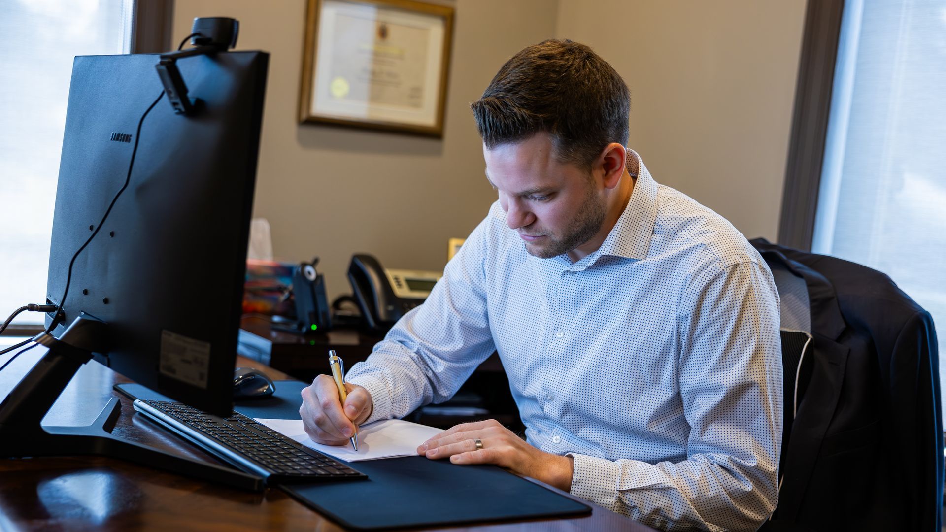 Dedicated professional writing notes at his desk, demonstrating the careful approach of chartered financial planners in Rayside.