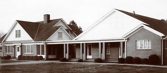 Single-story white house with a front porch and peaked roof on a cloudy day