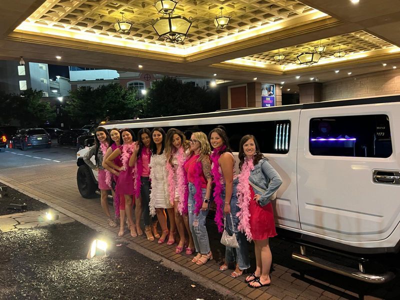 A group of women are standing in front of a white limousine.