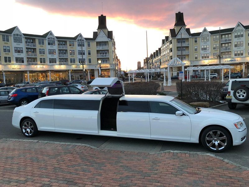 A white limousine is parked in front of a building.