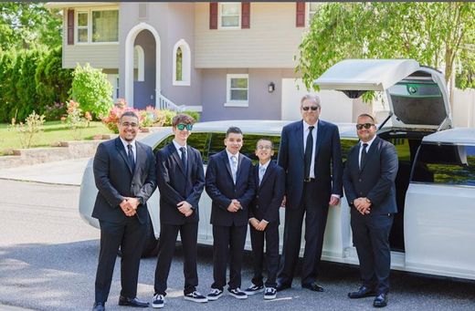 A group of men in suits and ties are standing in front of a white limousine.
