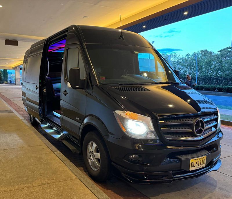 A black mercedes sprinter van is parked in a parking lot.