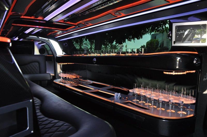 The inside of a limousine with a long table and lots of glasses on it.