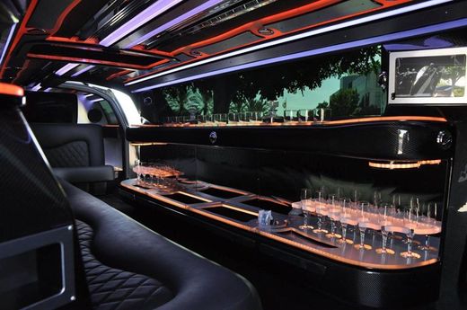 The inside of a limousine with a long table and lots of glasses on it.