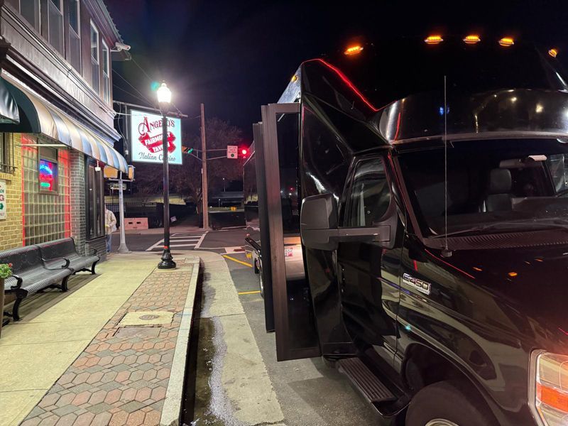 A black truck is parked in front of a restaurant at night