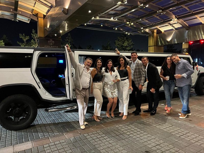 A group of people are standing in front of a white limousine.