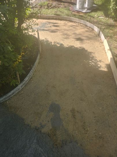 Curved gravel path with a white border, partly shaded by trees and sunlight.