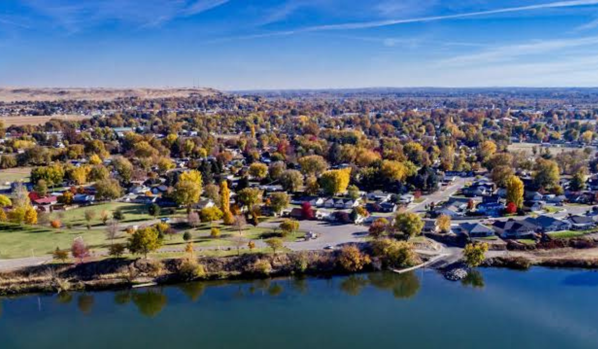 Aerial view of a lakeside neighborhood with autumn trees, houses, and calm water in the foreground
