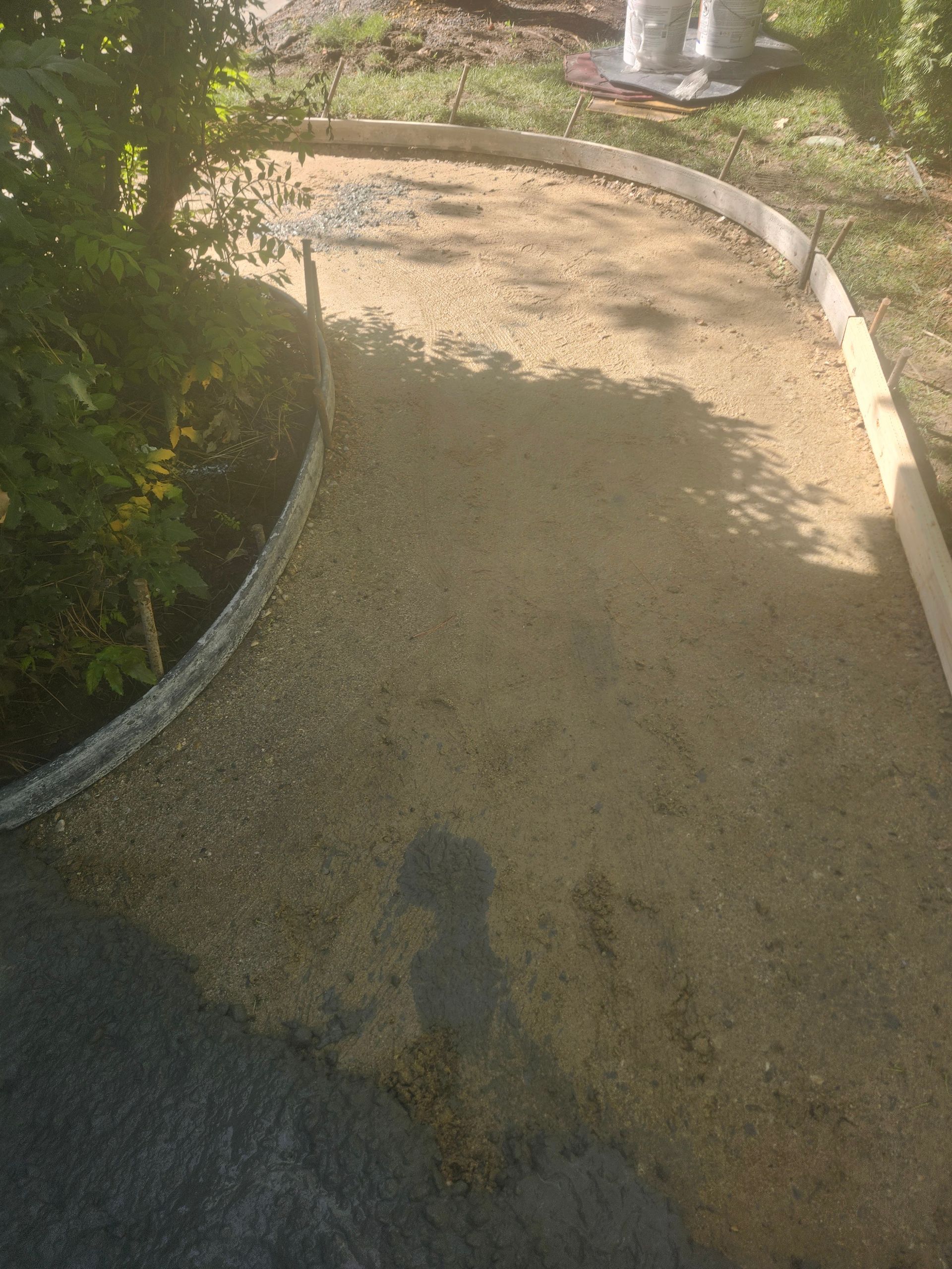 Curved gravel garden path bordered by white edging and greenery, lit by sunlight.
