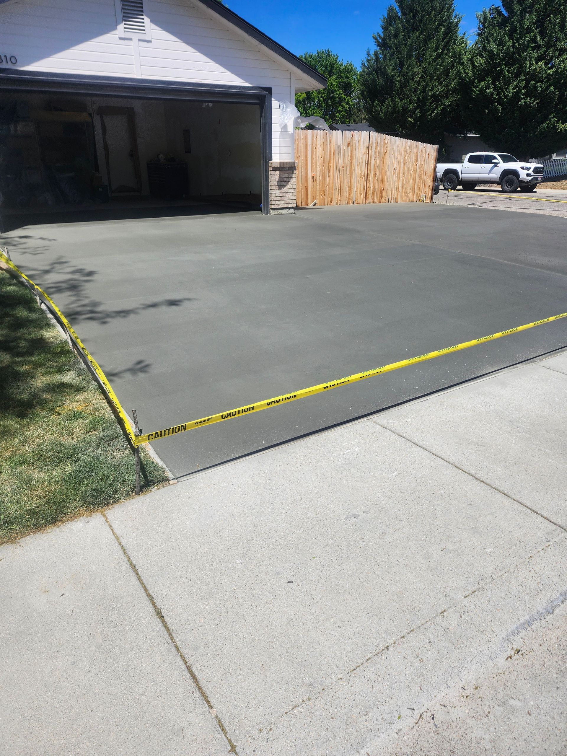 Driveway in front of a garage, with a yellow caution tape line across the pavement.