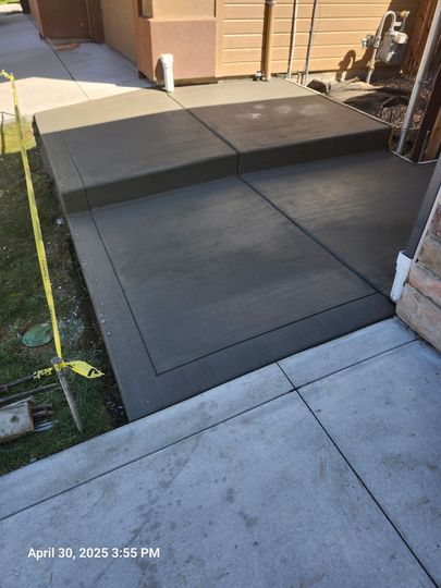 Concrete patio and walkway with a dark rubber mat ramp leading to a tan building entrance.