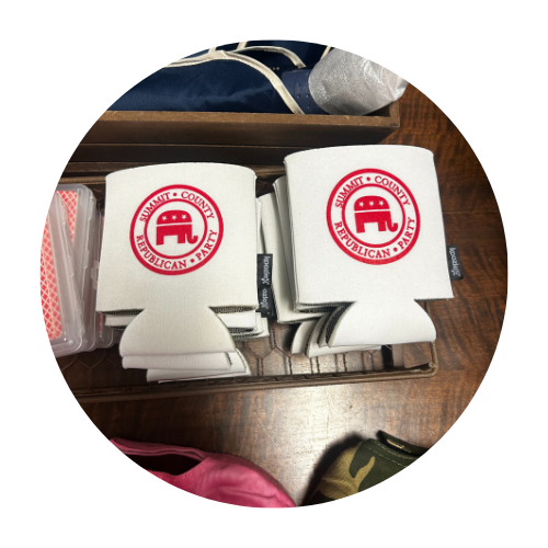 White koozies with a red Republican Party logo stacked on a wooden surface.