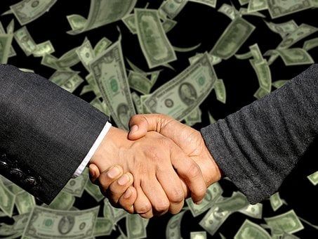 two hands shaking with money background