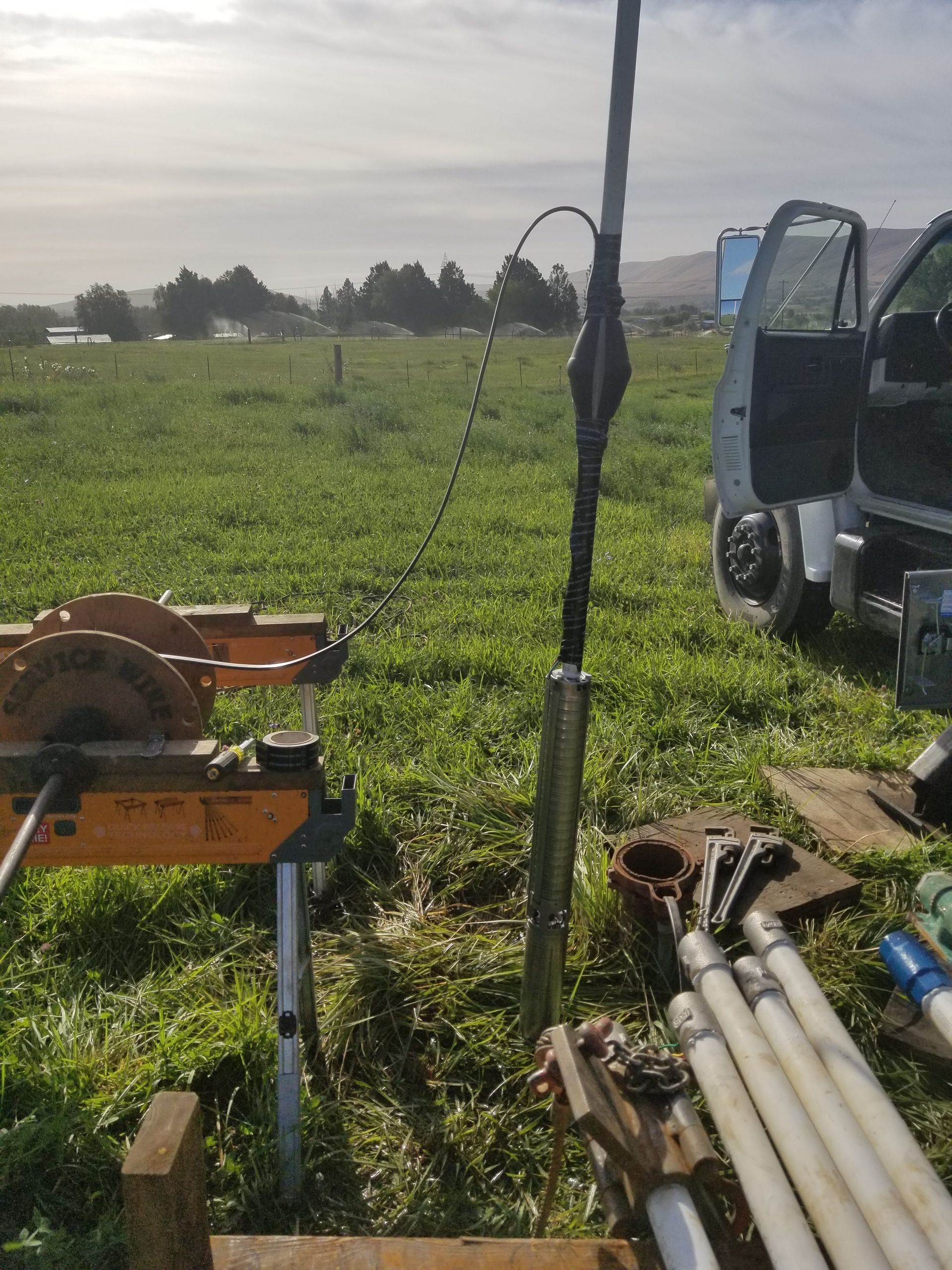 A truck is parked in a grassy field with its door open.