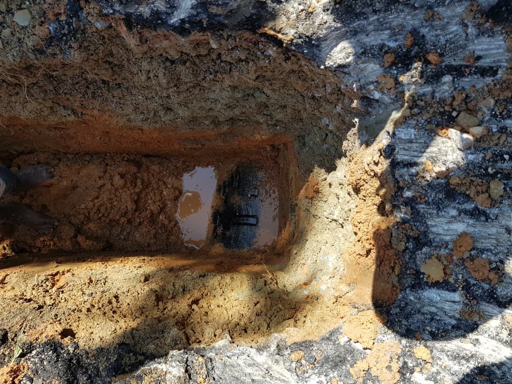 Trench Dug in Soil Reveals a Buried Black Pipe — Atherton Location Services In Atherton, QLD