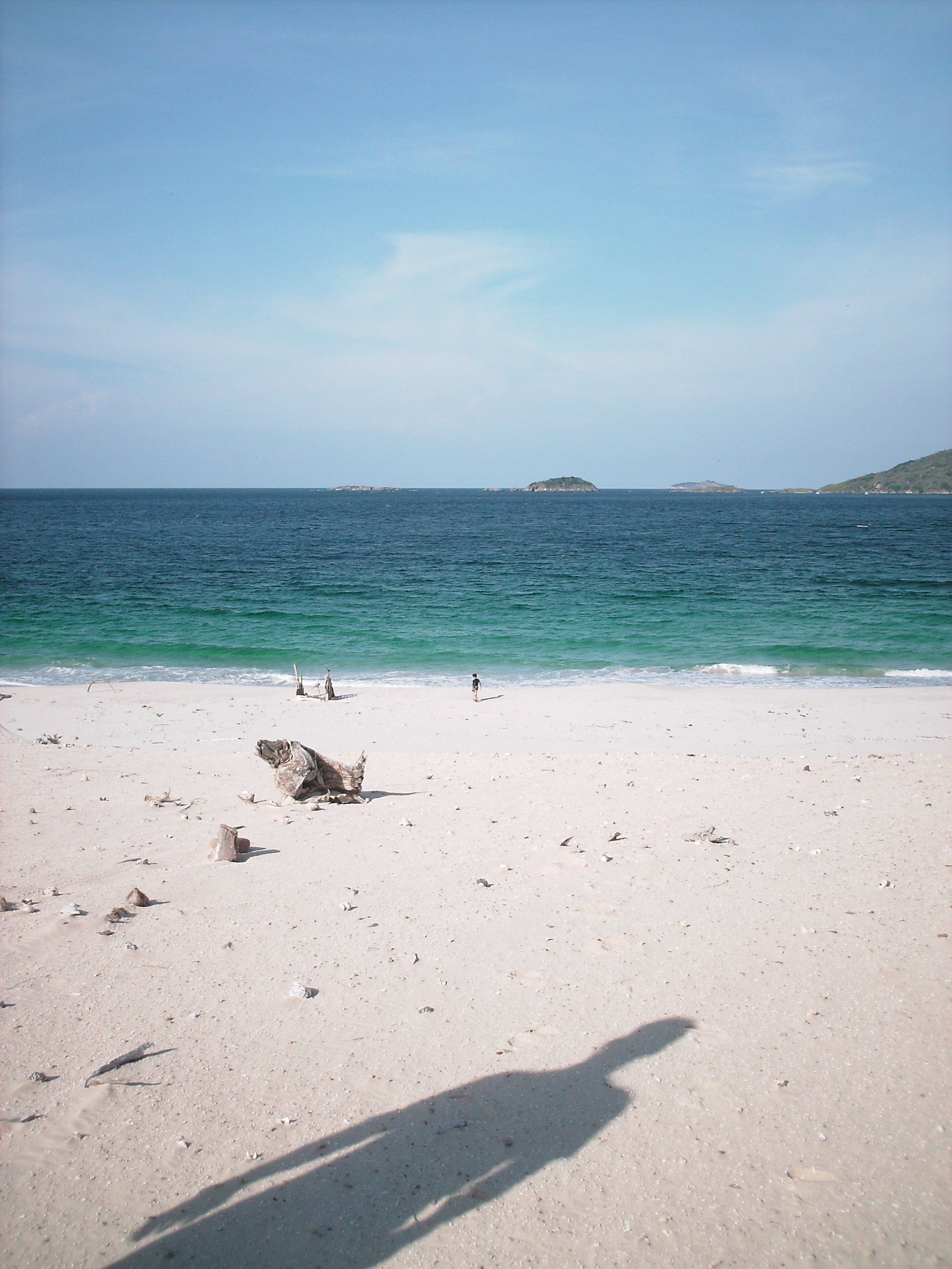 A shadow of a person is cast on a sandy beach