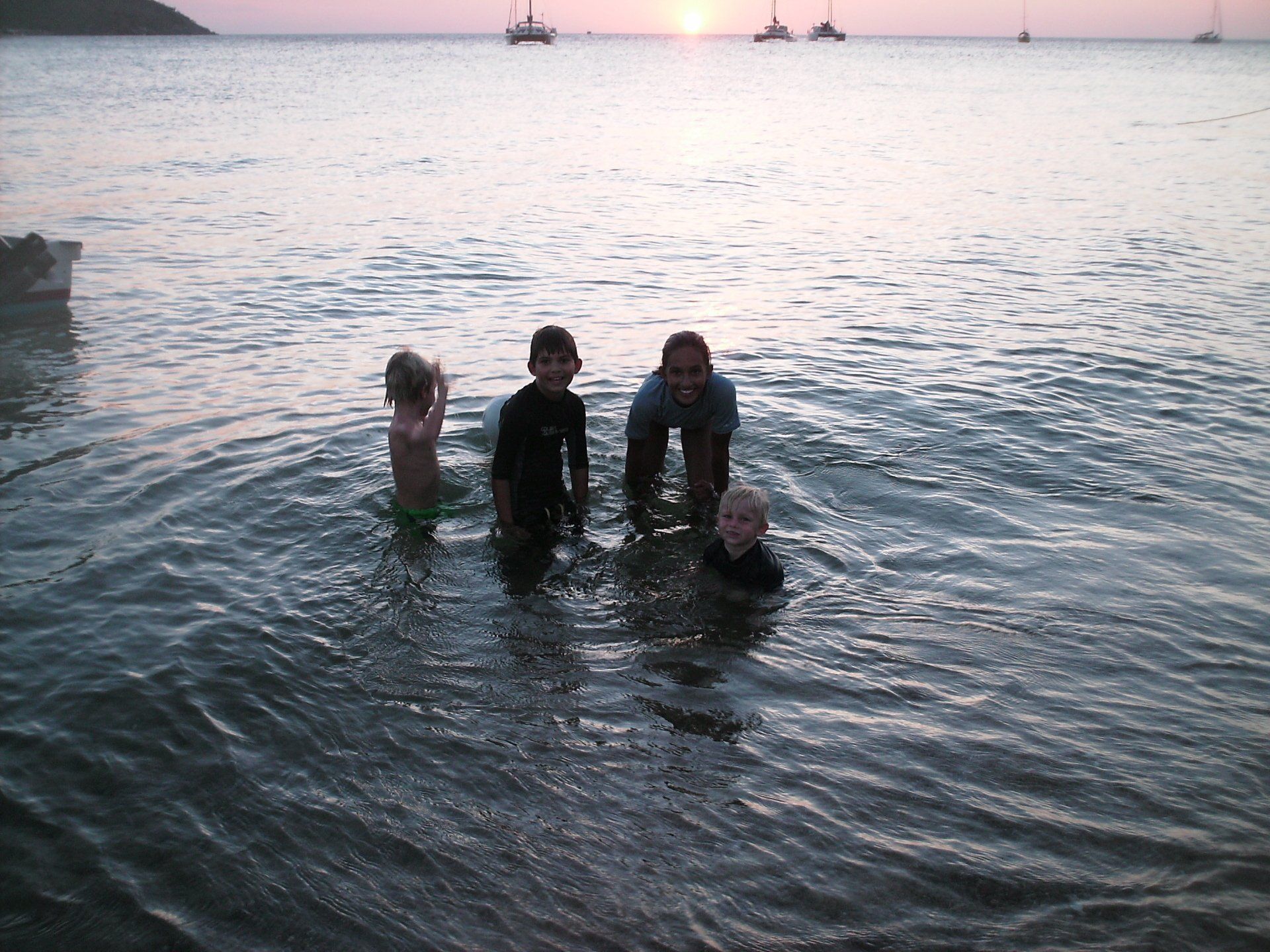 A group of children are playing in the water at sunset