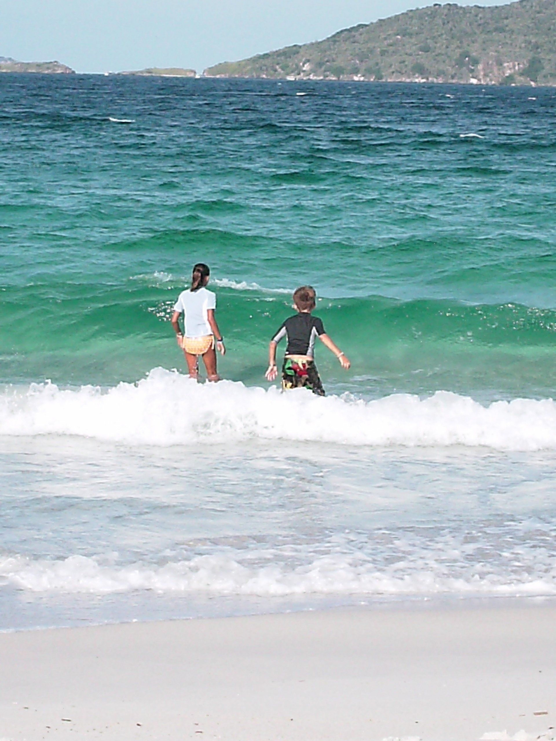 A boy and a girl are playing in the ocean