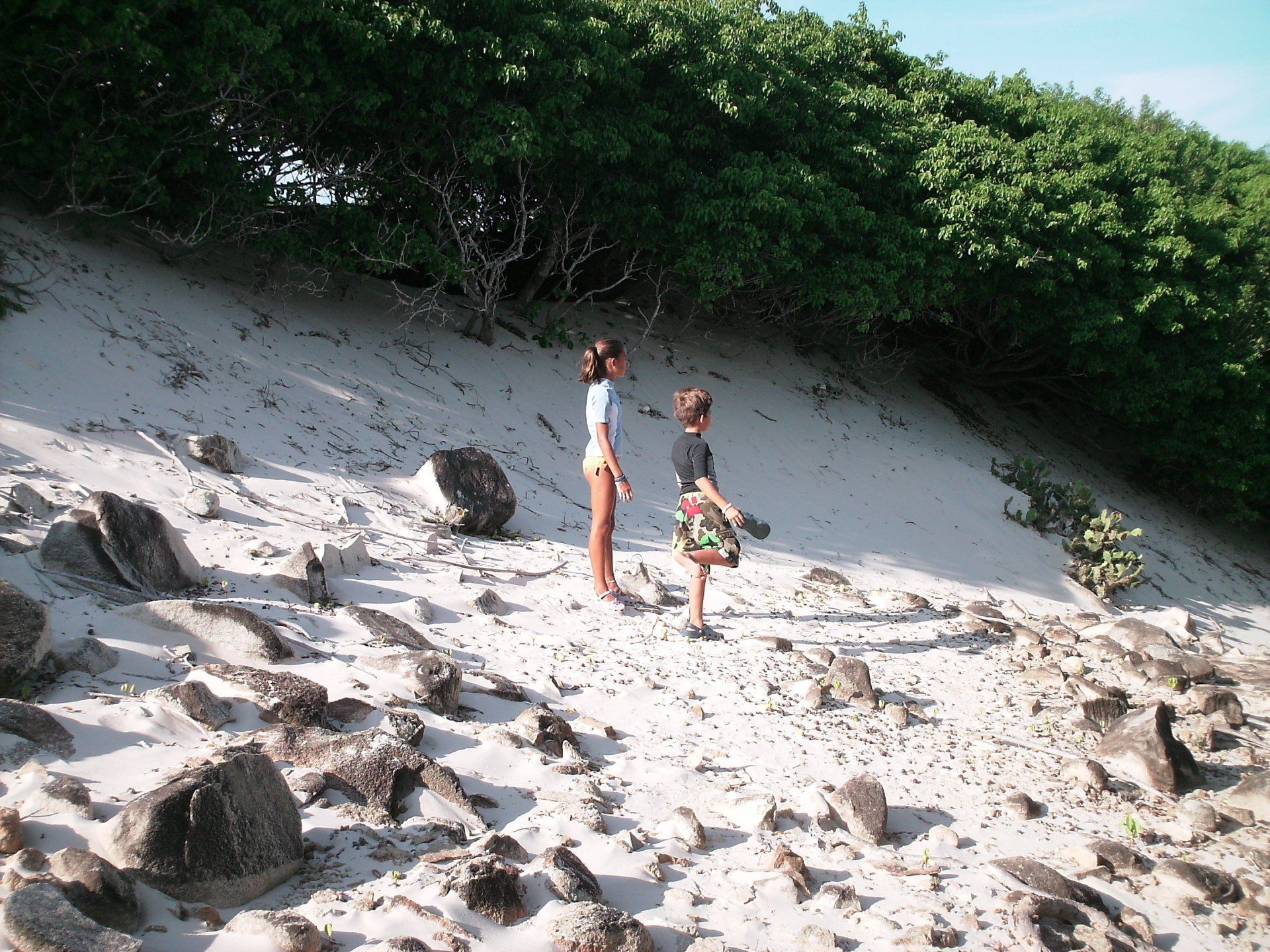 A boy and a girl standing on a sandy hill