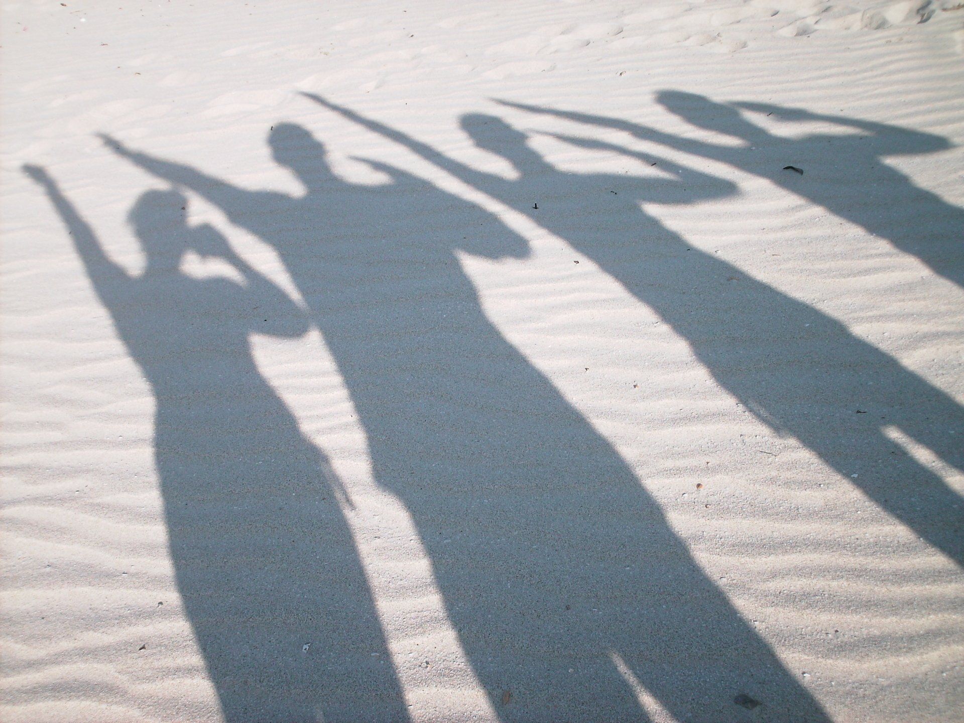 Shadows of people holding hands on a sandy beach