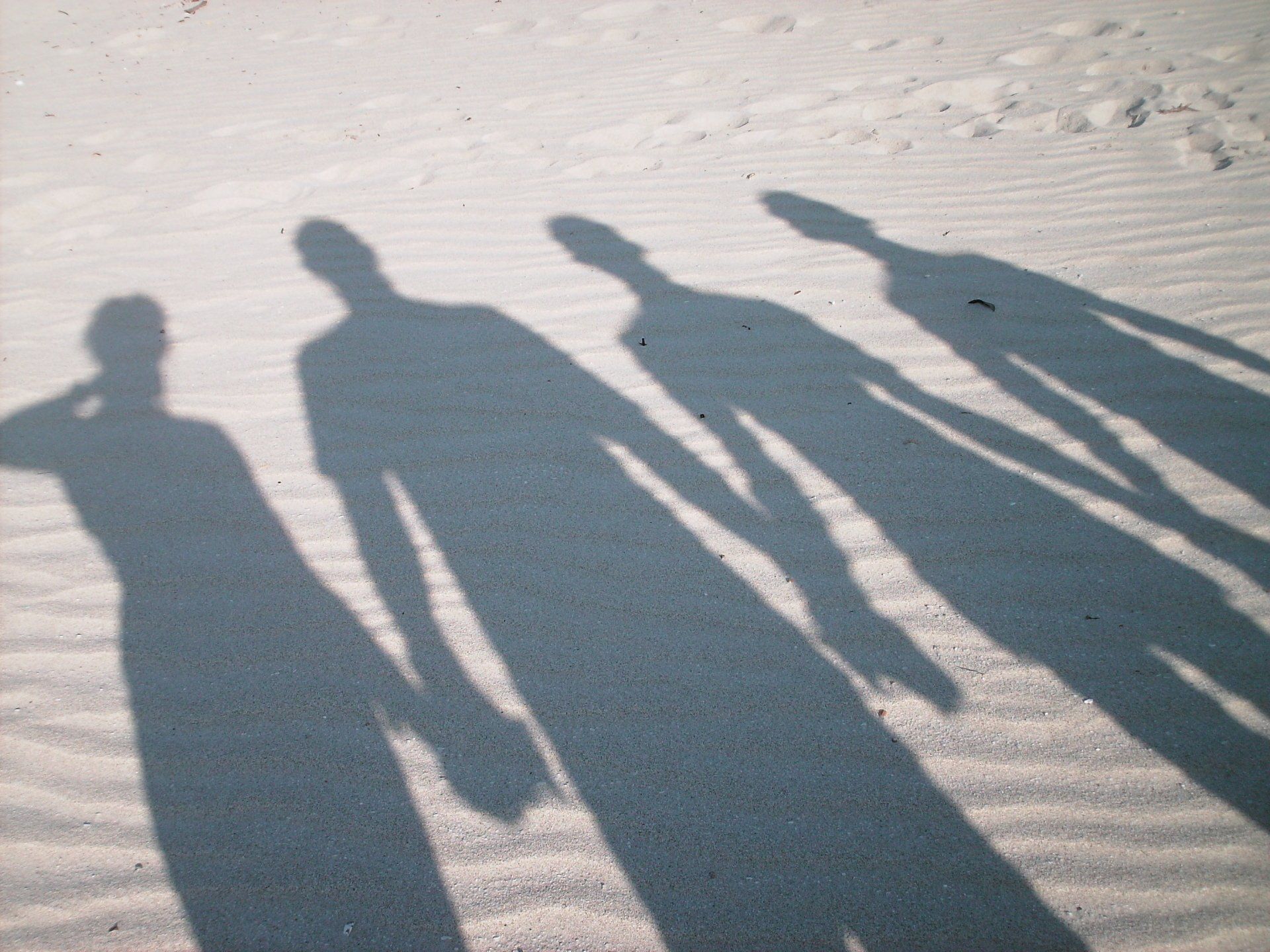 Shadows of people holding hands on a sandy beach