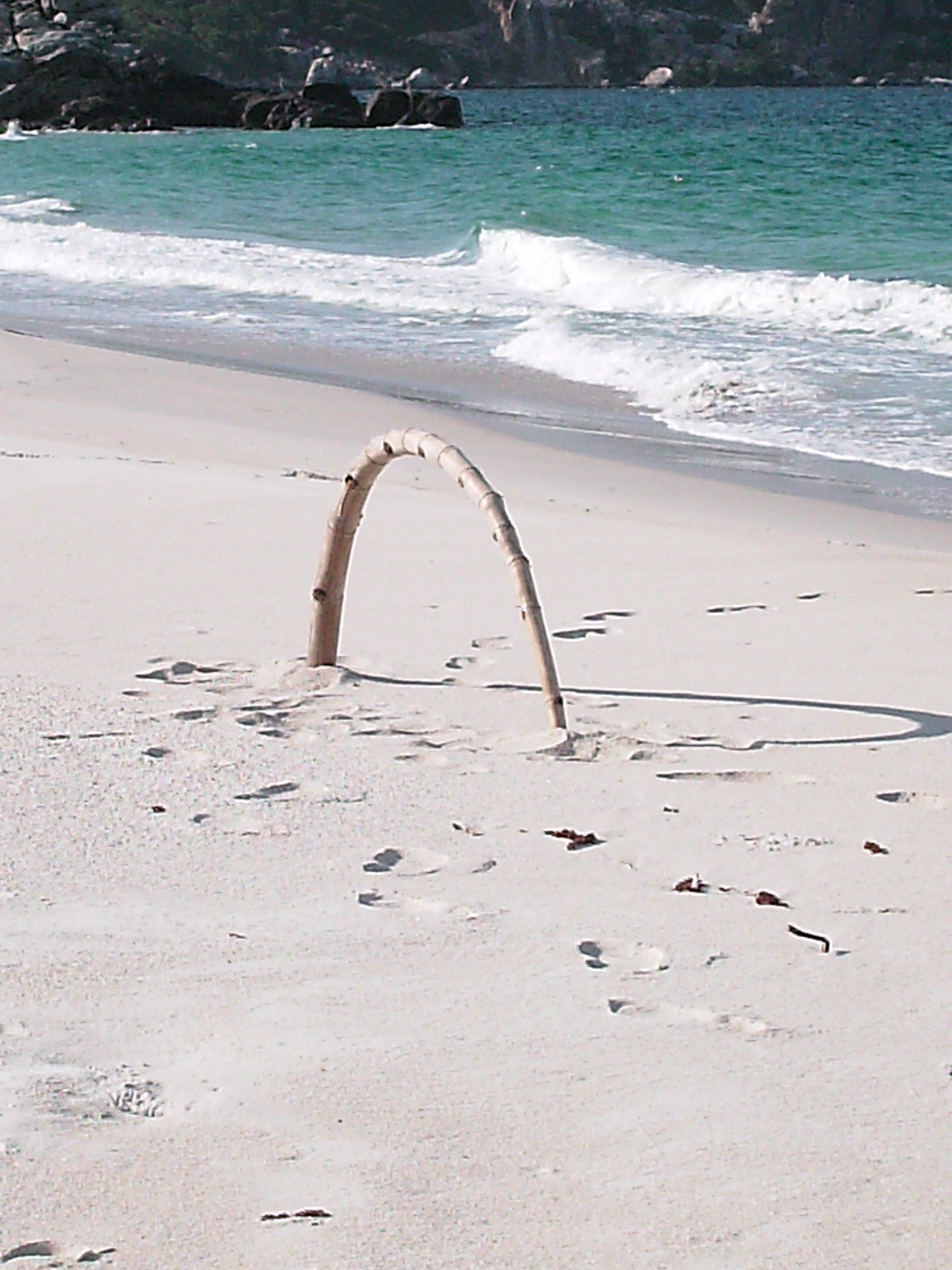 A sand arch on a beach with the ocean in the background