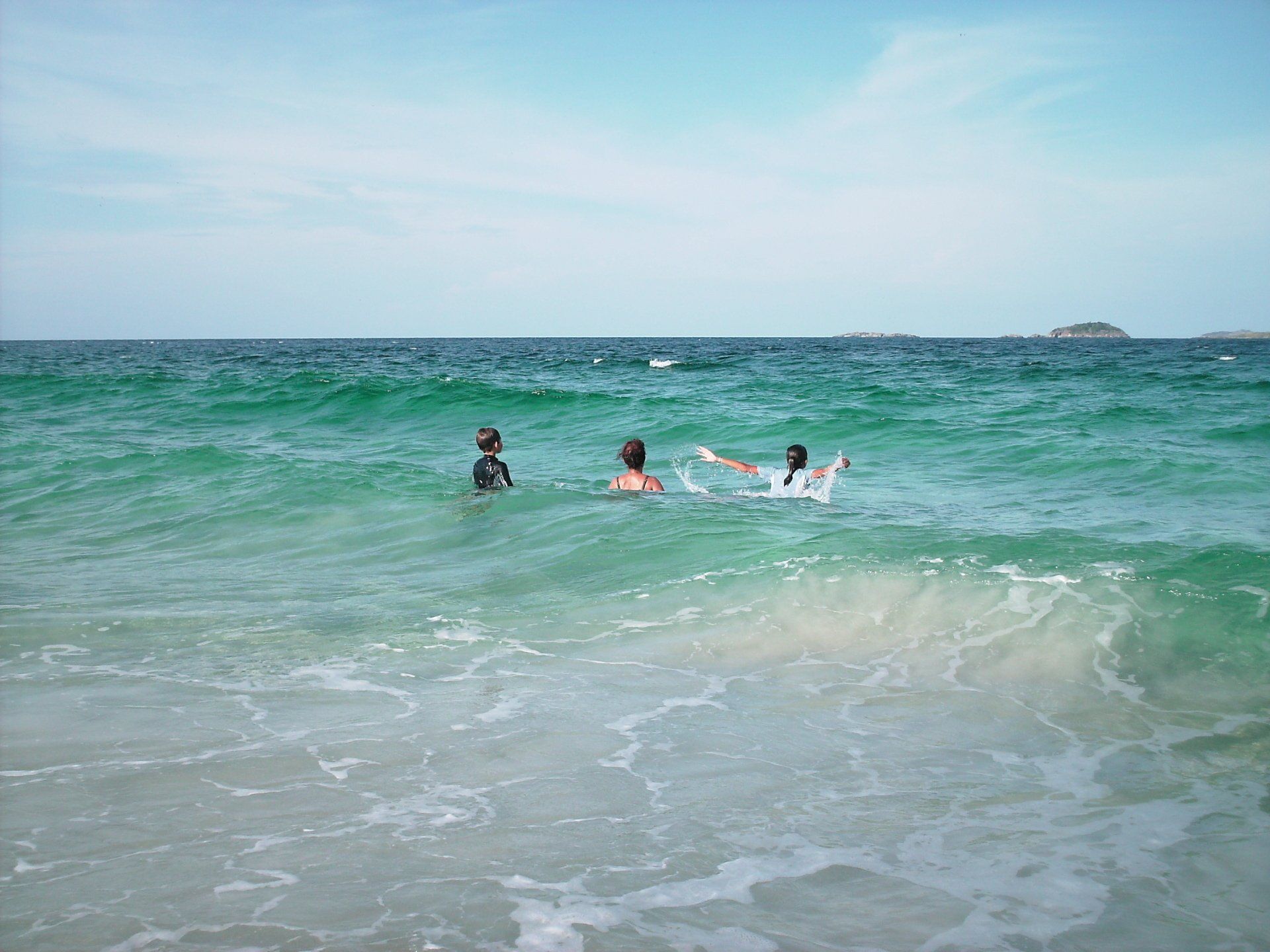 Two people are swimming in the ocean on a sunny day