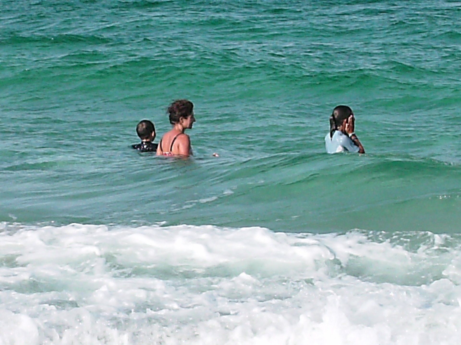 A woman and two children are swimming in the ocean