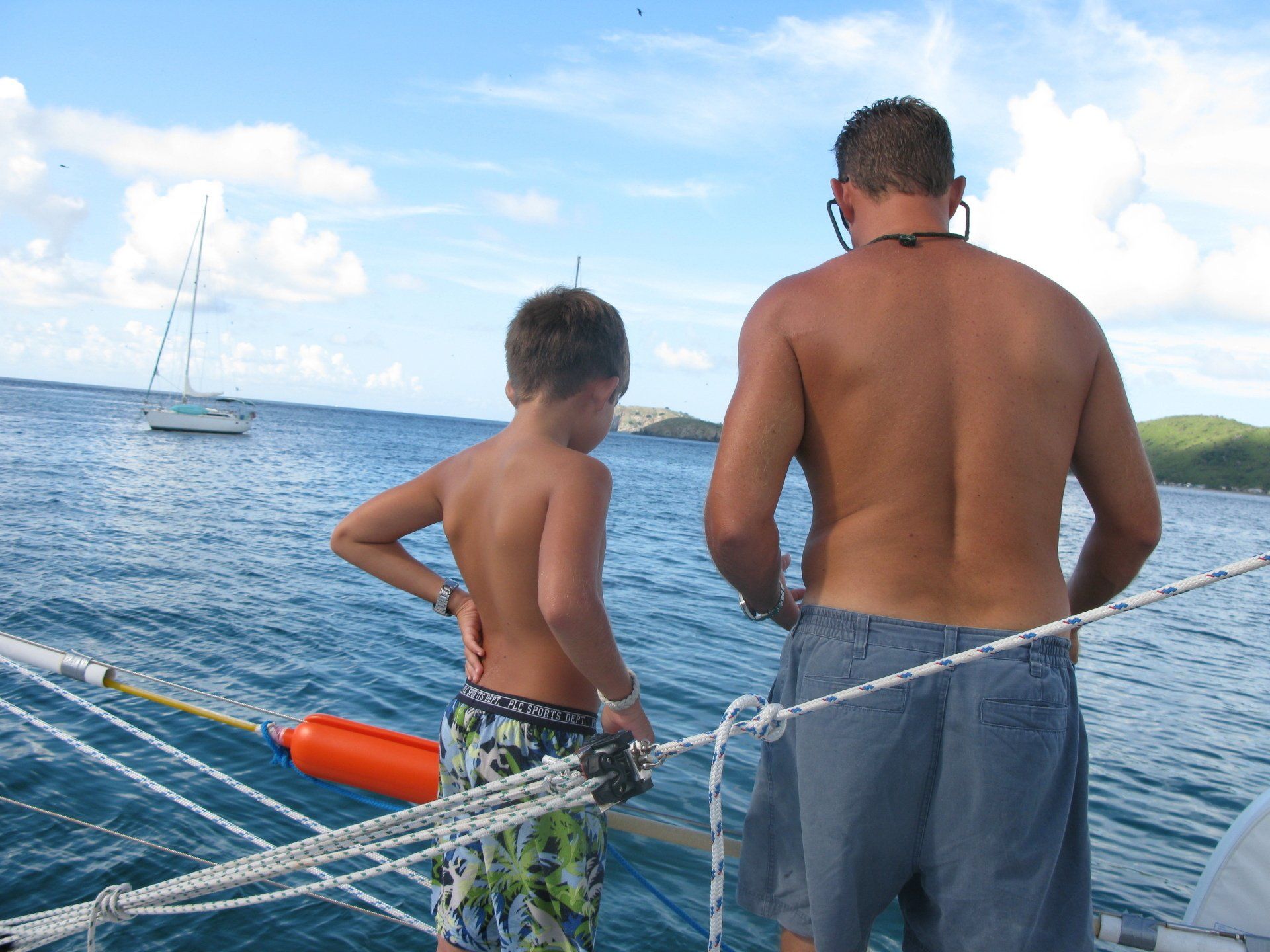 A man and a boy are standing on a boat in the ocean
