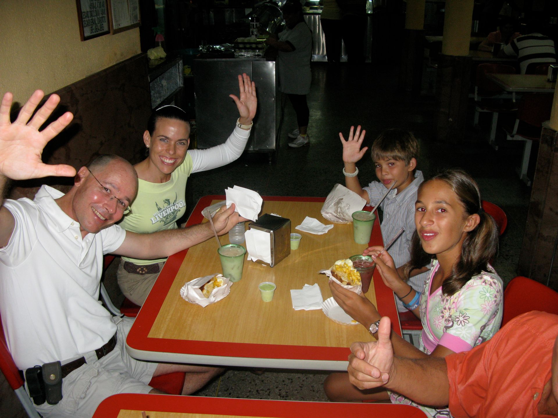 A group of people sitting at a table with their hands in the air