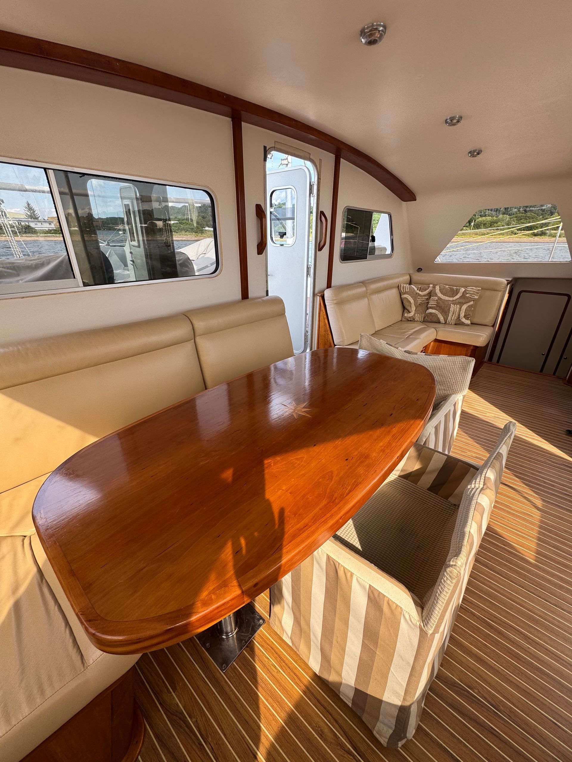 Chris White performance sailing catamaran Atlantic 48 ZEN private listing Rhode Island main salon and dining area with custom inlay teak compass rose